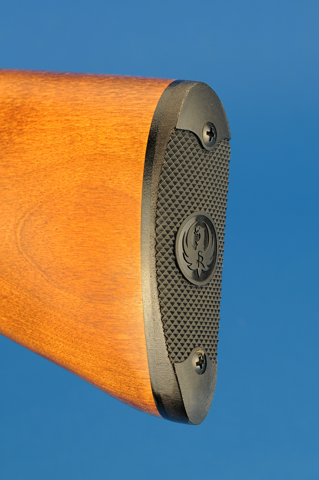 The model of the gun dictates how the stock will be finished. On this gun, there is a heavily-checkered plastic buttplate fitted to the stock with precision. Other guns might have a rubber pad, curved plastic or one that is fully adjustable.
